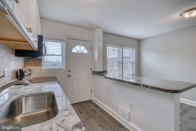 kitchen with white cabinets, kitchen peninsula, stainless steel range with electric stovetop, and a healthy amount of sunlight