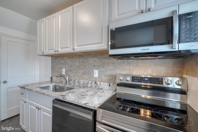 kitchen featuring appliances with stainless steel finishes, light stone countertops, decorative backsplash, sink, and white cabinets