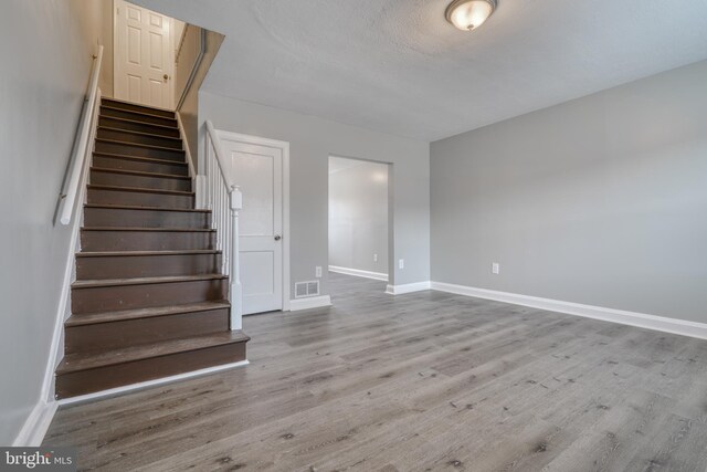 staircase with hardwood / wood-style floors and a textured ceiling