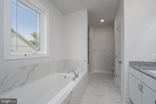 bathroom with toilet, vanity, tiled bath, and a healthy amount of sunlight