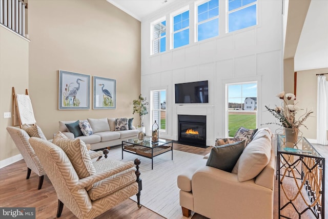 living room featuring hardwood / wood-style floors, ornamental molding, and a high ceiling