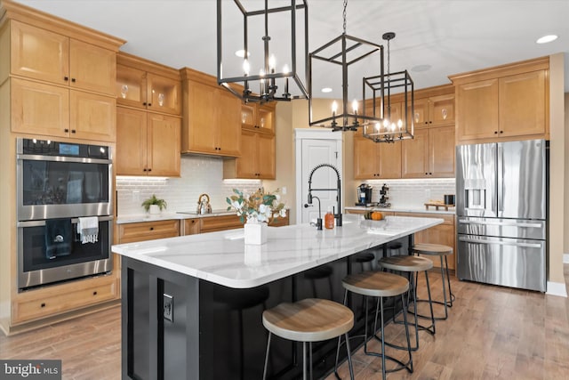 kitchen featuring hardwood / wood-style floors, appliances with stainless steel finishes, and a kitchen island with sink