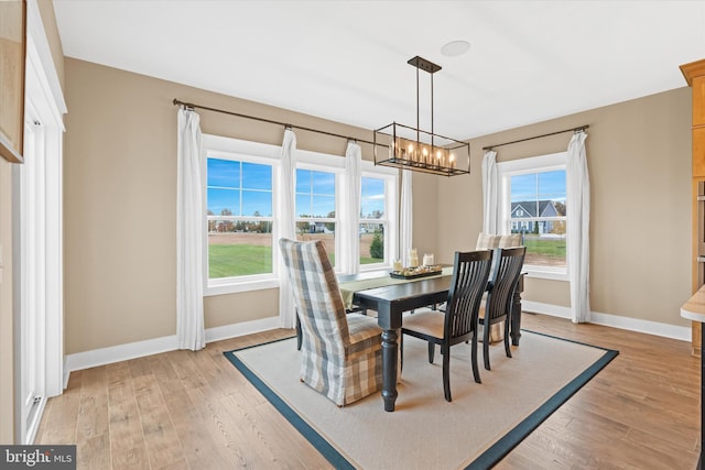 dining space with an inviting chandelier and light hardwood / wood-style flooring