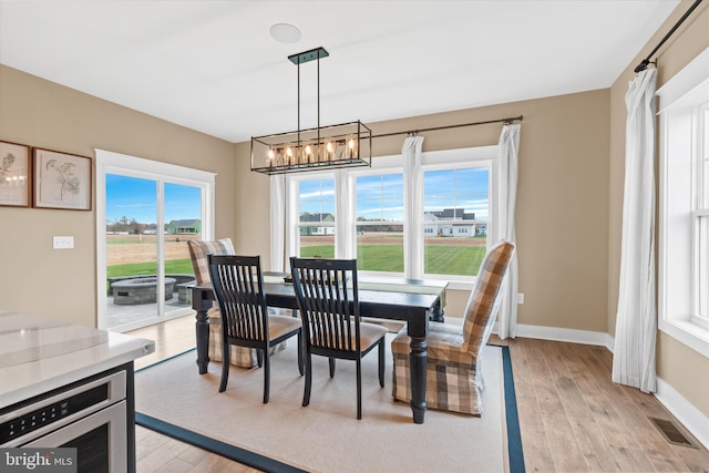 dining space with light hardwood / wood-style flooring and a chandelier