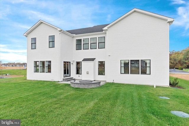 back of house featuring an outdoor fire pit and a yard