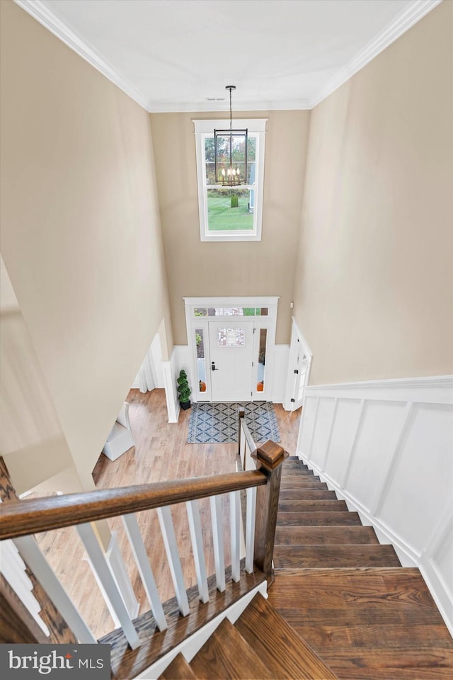 stairs featuring hardwood / wood-style flooring, a notable chandelier, and ornamental molding