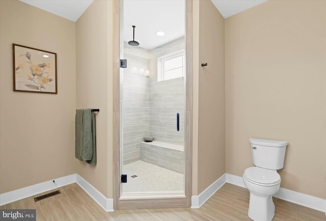 bathroom featuring toilet, hardwood / wood-style flooring, and a shower with shower door