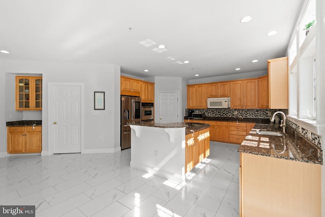 kitchen with dark stone counters, decorative backsplash, sink, a kitchen island, and appliances with stainless steel finishes