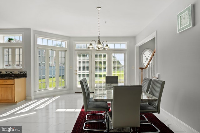 dining room featuring plenty of natural light, light tile patterned floors, and a notable chandelier