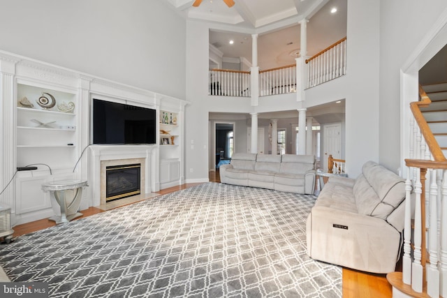 living room featuring ceiling fan, a towering ceiling, and a high end fireplace