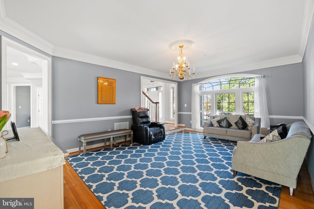 living room with hardwood / wood-style flooring, a chandelier, and crown molding