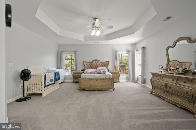 carpeted bedroom featuring ornamental molding, ceiling fan, and a tray ceiling