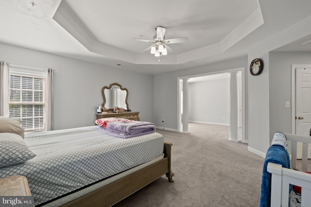 bedroom with light colored carpet, decorative columns, ornamental molding, ceiling fan, and a tray ceiling