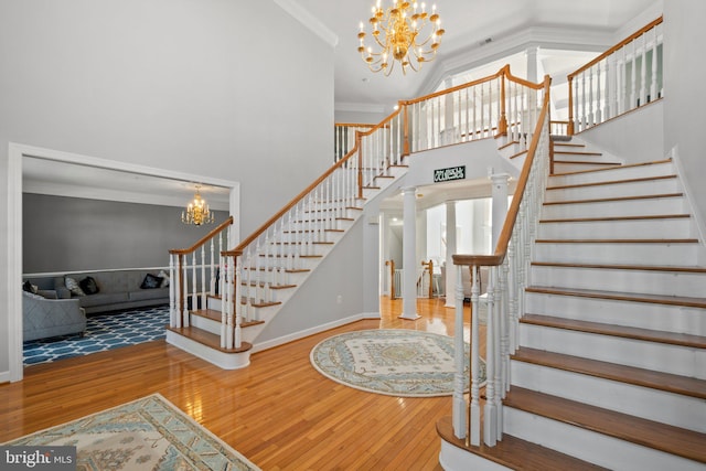 foyer with ornamental molding, hardwood / wood-style flooring, decorative columns, and an inviting chandelier