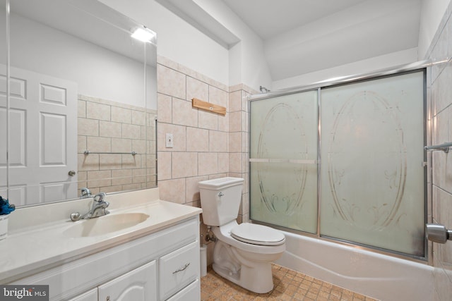 full bathroom featuring vanity, combined bath / shower with glass door, tile walls, and toilet