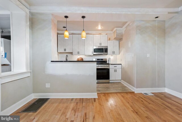 kitchen featuring hanging light fixtures, tasteful backsplash, light hardwood / wood-style flooring, white cabinets, and appliances with stainless steel finishes