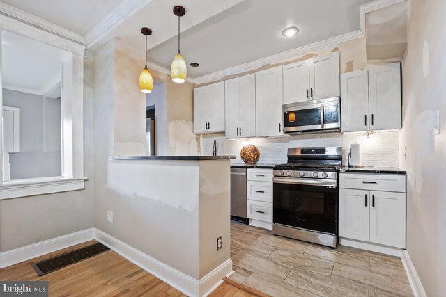 kitchen with white cabinetry, light hardwood / wood-style flooring, stainless steel appliances, and ornamental molding