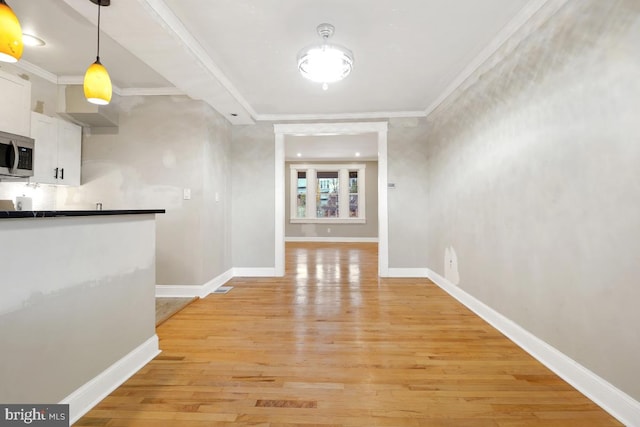 hall with crown molding and light hardwood / wood-style flooring