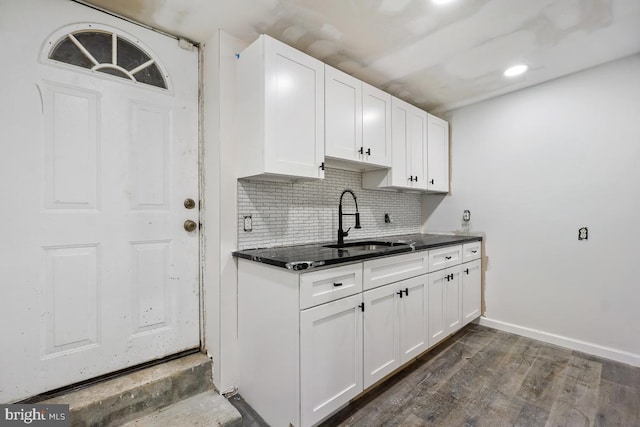 kitchen with decorative backsplash, dark hardwood / wood-style flooring, white cabinetry, and sink