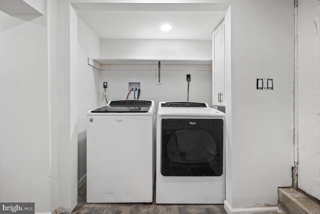 washroom with dark hardwood / wood-style flooring, washer and clothes dryer, and cabinets