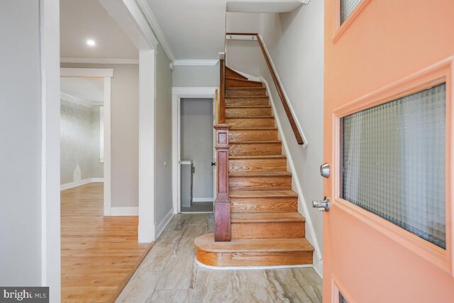 staircase with hardwood / wood-style flooring and ornamental molding