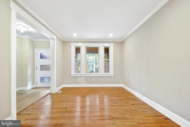 spare room with light hardwood / wood-style floors, ornamental molding, and a notable chandelier