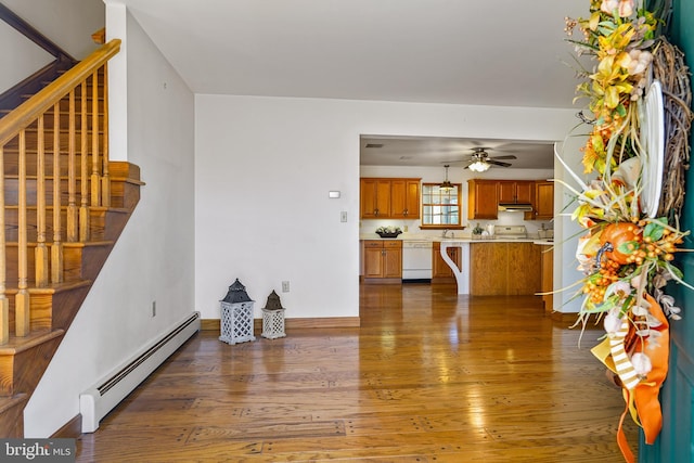 living room featuring baseboard heating, dark hardwood / wood-style floors, ceiling fan, and sink