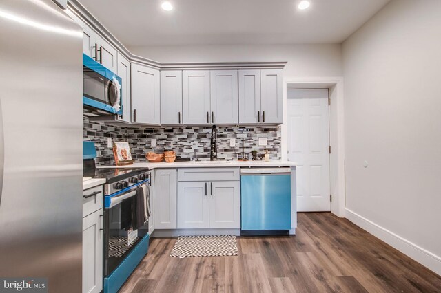 kitchen featuring appliances with stainless steel finishes, sink, tasteful backsplash, and dark hardwood / wood-style flooring