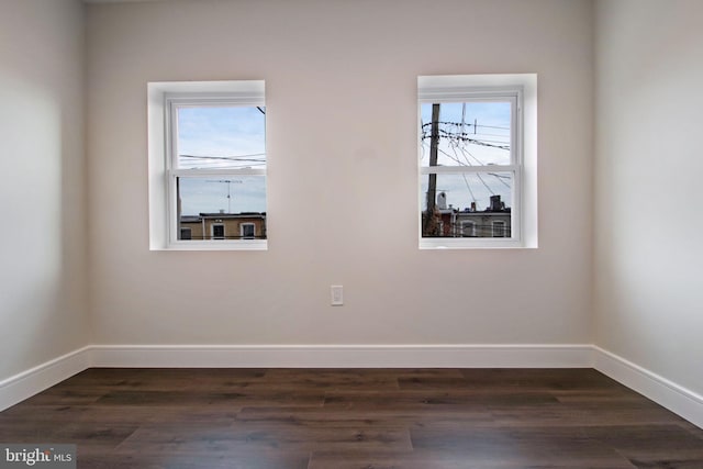 spare room featuring plenty of natural light and dark hardwood / wood-style flooring