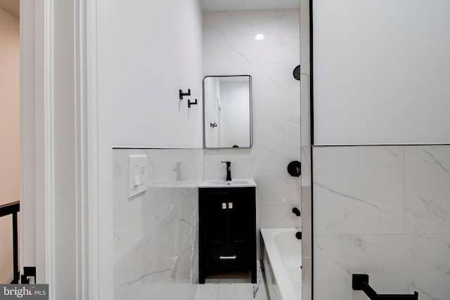 bathroom featuring tile walls, tiled shower / bath combo, and vanity