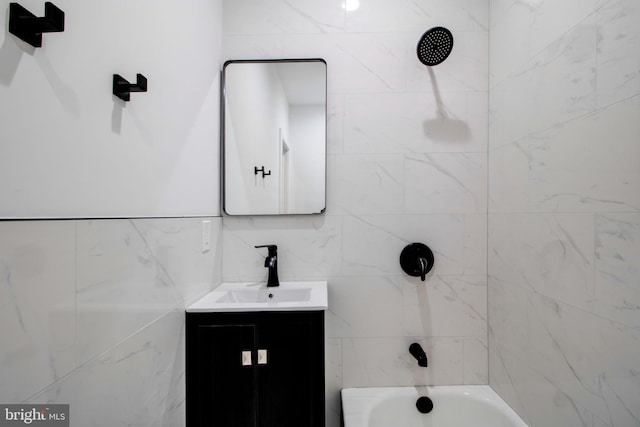 bathroom featuring vanity, tiled shower / bath combo, and tile walls