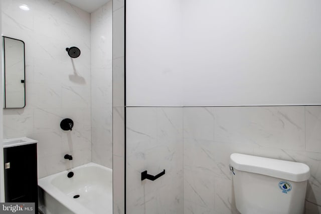 full bathroom with toilet, vanity, tiled shower / bath combo, and tile walls