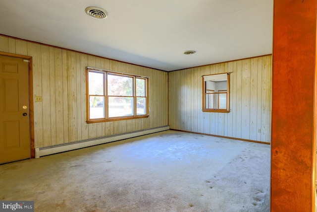 carpeted spare room with baseboard heating and wooden walls