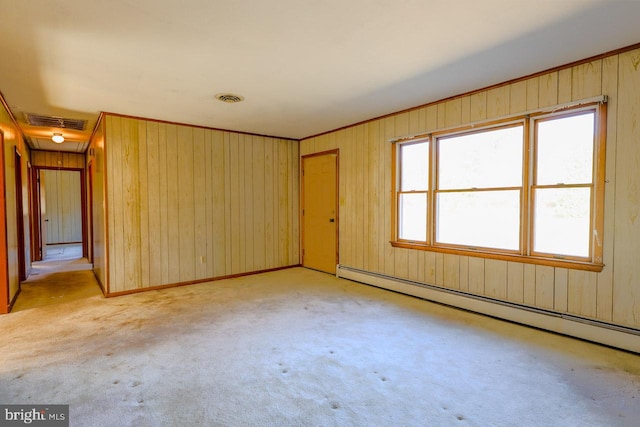 carpeted spare room with wooden walls and a baseboard heating unit