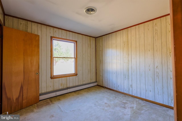 empty room featuring light colored carpet, baseboard heating, and wooden walls