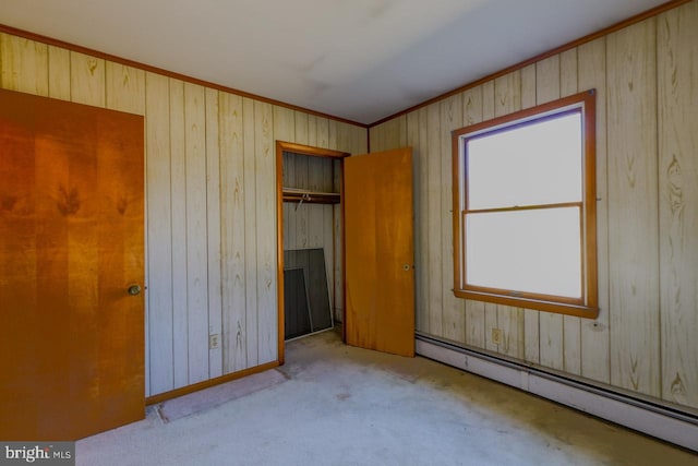 unfurnished bedroom with wooden walls, a closet, light colored carpet, and a baseboard radiator