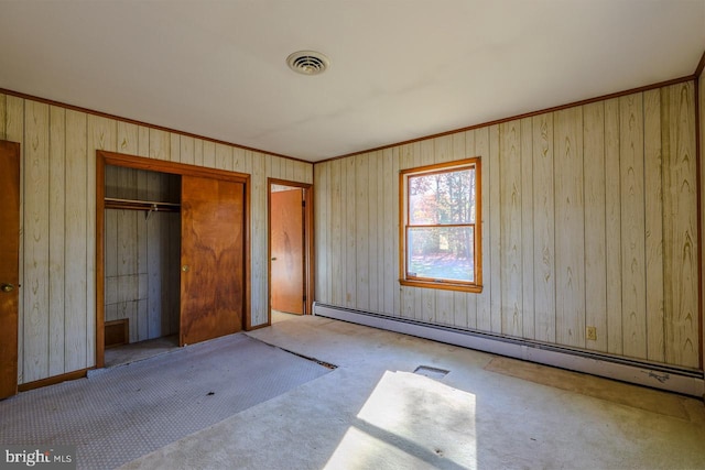 unfurnished bedroom featuring wooden walls, a closet, and a baseboard radiator