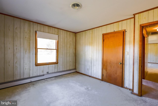 unfurnished room with wood walls, light carpet, and a baseboard heating unit