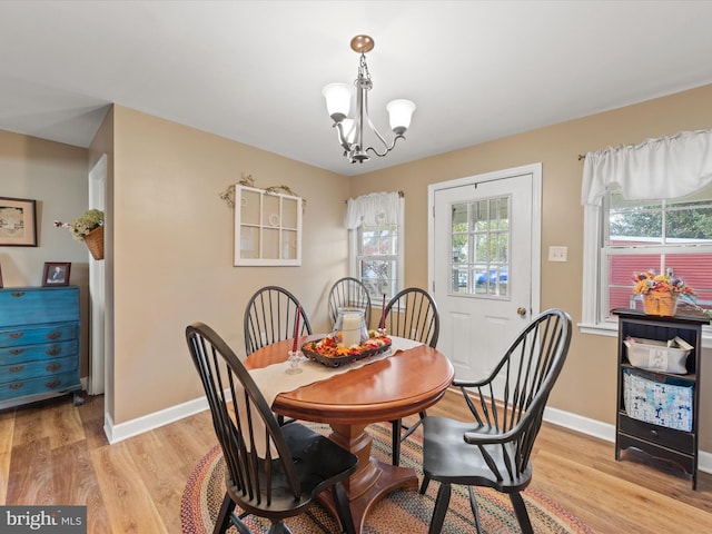 dining space with a healthy amount of sunlight, light hardwood / wood-style flooring, and a notable chandelier