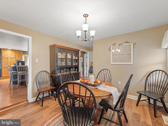 dining space with light hardwood / wood-style floors and a chandelier