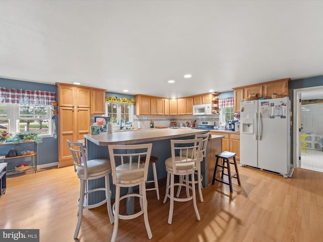 kitchen featuring white appliances, a breakfast bar area, light wood-type flooring, and a kitchen island