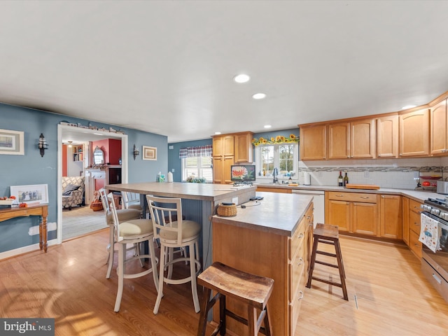 kitchen featuring a kitchen breakfast bar, light hardwood / wood-style flooring, dishwashing machine, and a kitchen island