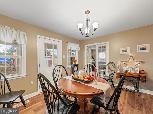 dining space with a chandelier, a wealth of natural light, and light hardwood / wood-style flooring