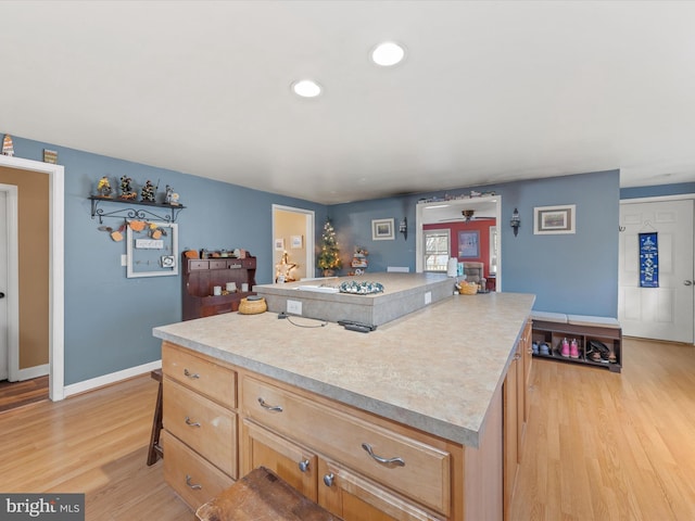 kitchen featuring a kitchen bar, light wood-type flooring, light brown cabinets, and a kitchen island