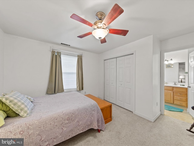 carpeted bedroom with a closet, sink, ceiling fan, and ensuite bathroom