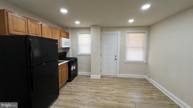 kitchen featuring light hardwood / wood-style floors, plenty of natural light, and black appliances