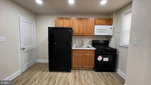 kitchen featuring sink, light hardwood / wood-style floors, and black appliances