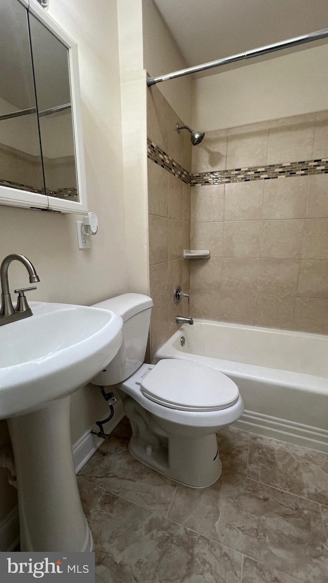 full bathroom featuring tiled shower / bath combo, toilet, and sink