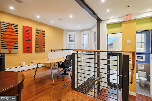 office with wood-type flooring and a baseboard heating unit