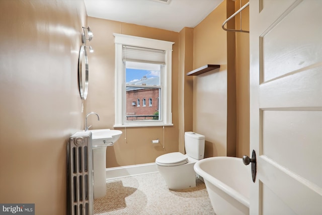 bathroom with tile patterned flooring, a washtub, and toilet